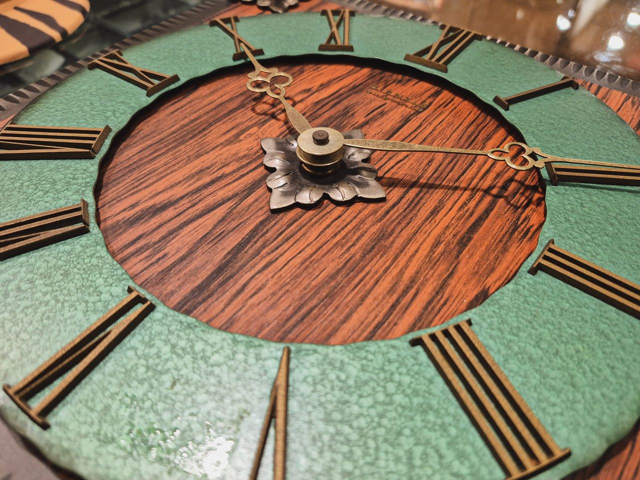 Close-up of an elegant vintage clock with Roman numerals and woodgrain texture.