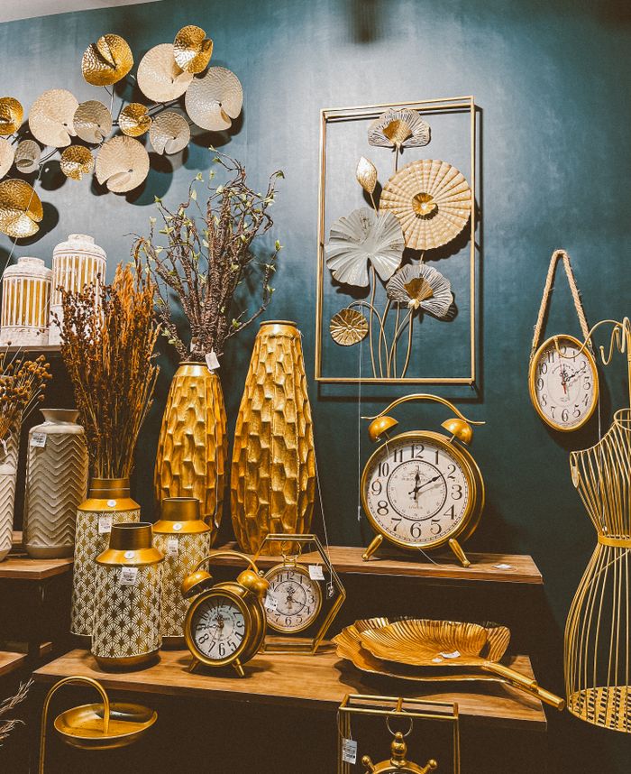Stylish arrangement of gold and green decor items including clocks, vases, and wall art.