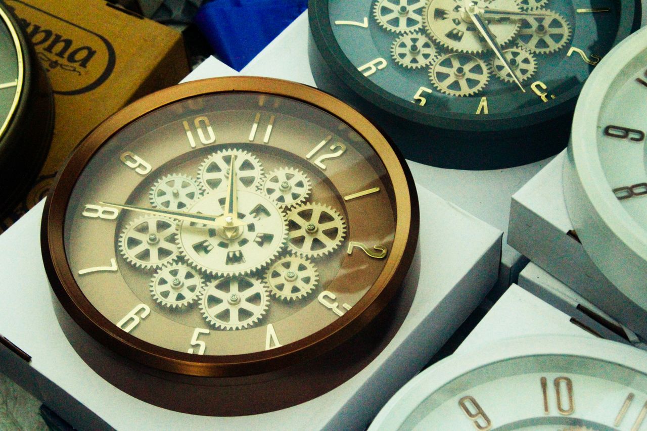 Close-up of steampunk-inspired wall clocks with visible gears in a retail setting.