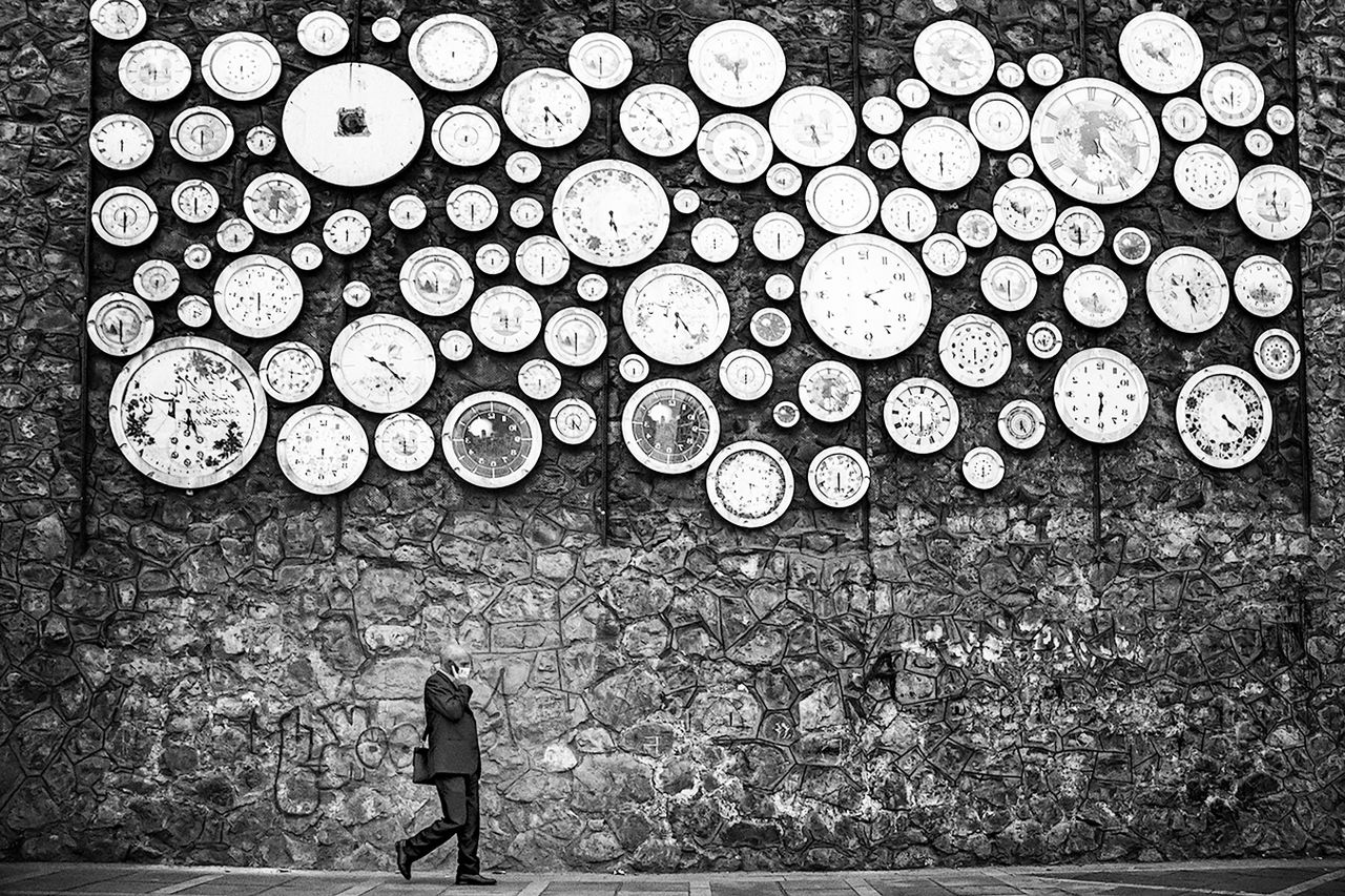 Man walks past unique clock wall installation in Tehran, Iran.